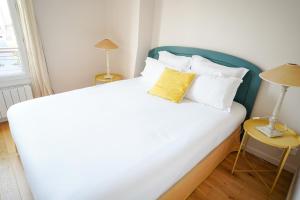 - une chambre avec un grand lit blanc et un oreiller jaune dans l'établissement Villa Escudier Appart-hôtel, à Boulogne-Billancourt