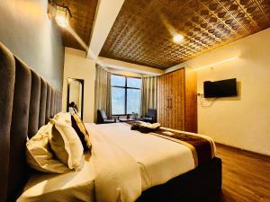 a bedroom with a large bed and a television at White Rose Hotel in Manāli