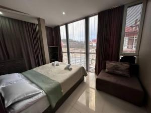 a bedroom with a bed and a chair and windows at Glass House Bakuriani in Bakuriani