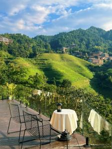 a table and chairs on a balcony with a view at Lost In Beauty Guest House 龙脊梯田野望民宿 in Longsheng