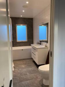 La salle de bains est pourvue de toilettes, d'un lavabo et d'une baignoire. dans l'établissement Topp modern Villa 200m från havet nära centrum och natur, à Stenungsund