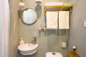 ein Badezimmer mit einem Waschbecken, einem WC und einem Spiegel in der Unterkunft Shanghai Hills & Well-time Homestay in Shanghai