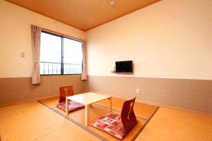 una camera con tavolo, due sedie e una TV di 民宿ふくだ a Minamiōsaka