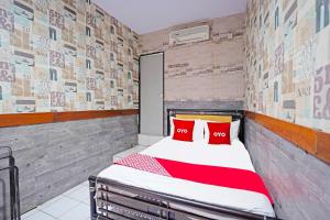 a bedroom with a bed with red pillows on it at OYO 91415 De Wijaya Hotel in Bungurasih