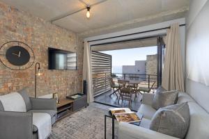 a living room with a couch and a tv on a brick wall at Manhattan on Coral 7 in Bloubergstrand