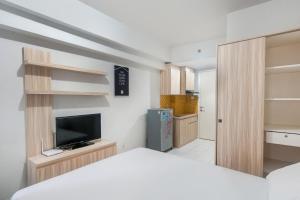 a bedroom with a bed and a tv and shelves at OYO Life 2837 Apartment Dramaga Tower in Bogor