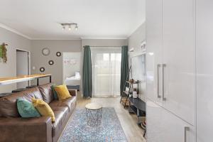 sala de estar con sofá marrón y dormitorio en Nirvana 12 en Bloubergstrand