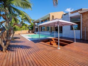 a house with a wooden deck with an umbrella at One on Chelsea in Durban