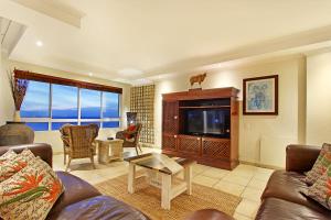 een woonkamer met een bank en een tv bij Ocean View C602 by HostAgents in Bloubergstrand