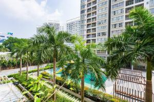a pool with palm trees in front of a tall building at Lee's apartment at Scenicvalley in Ho Chi Minh City