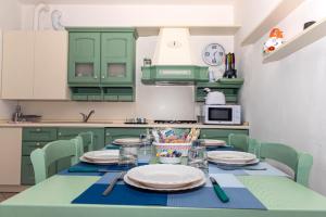 uma cozinha com armários verdes e uma mesa com pratos em La casa di Gabry in residence con piscina comune em Tavernola Bergamasca