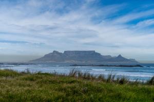 een uitzicht op een berg in de oceaan met een strand bij Eden on the Bay Luxury Apartments, Blouberg, Cape Town in Bloubergstrand