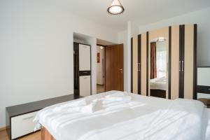a bedroom with a white bed and a mirror at Renovated Gem Plumbuita Park in Bucharest