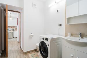 a bathroom with a washing machine and a sink at Renovated Gem Plumbuita Park in Bucharest