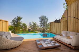 a patio with two chairs and a table and a pool at Katara Hills Doha, Lxr Hotels & Resorts in Doha