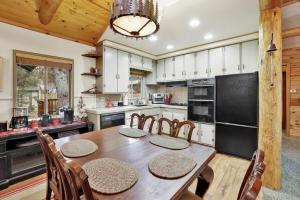 a kitchen with a table and chairs and a black refrigerator at 2417-Timber Pines Chalet cabin in Big Bear Lake