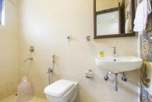 ein Badezimmer mit einem Waschbecken, einem WC und einem Spiegel in der Unterkunft Aravind Residency Calangute in Goa