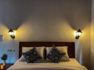 1 dormitorio con 1 cama con 2 luces en la pared en TM DARTA Homestay UBUD, en Ubud