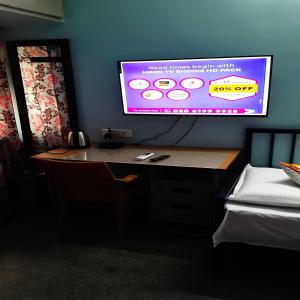 a desk in a room with a tv on the wall at Konnectify Quintuple - 5 Person Room Suite in Coimbatore