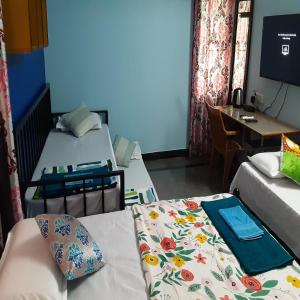 a room with two beds and a table and a desk at Konnectify Quintuple - 5 Person Room Suite in Coimbatore