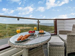 a table with two glasses of orange juice and food on a balcony at 3 Bed in Newquay SPINS in Newquay