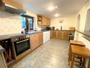 a kitchen with wooden cabinets and a tile floor at 2 Bed in Bude DBANK in Holsworthy
