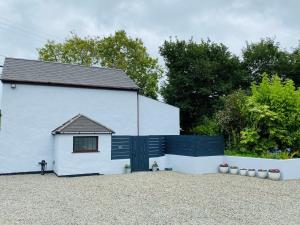 a white house with a black door and a fence at 2 Bed in Bude DBANK in Holsworthy