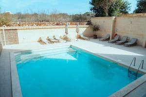 a swimming pool with chairs and a swimming pool at Luxurious Gozo Apartment, Qala in Qala