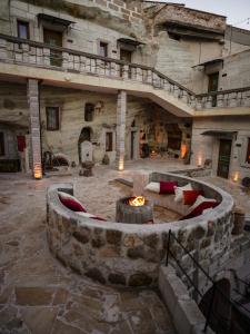 a stone building with a fire pit in a courtyard at Lost City Cappadocia Cave Hotel in Nar