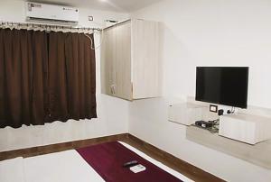Aravind Residency Calangute في Goa: غرفة مع تلفزيون بشاشة مسطحة على الحائط