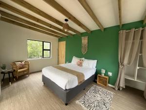 1 dormitorio con cama y pared verde en Forest Gate Estate en Plettenberg Bay