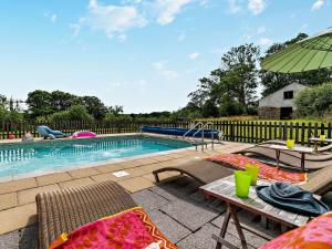 a swimming pool with chairs and a table and an umbrella at 2 Bed in Crackington Haven 02038 in North Petherwin