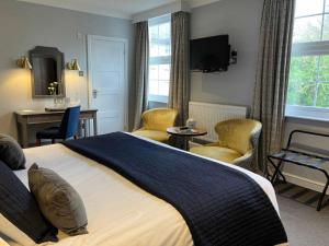 a bedroom with a large bed with chairs and a desk at Budock Vean Hotel in Falmouth