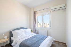a white bedroom with a bed and a window at City Oasis: Newly Renovated 2Br Apt in City Center in Athens