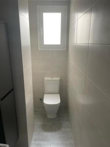 a bathroom with a white toilet with a window at Carbo Home moderno, Algemesi Home in Algemesí
