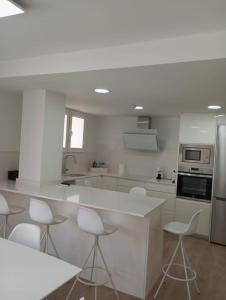 a kitchen with white counters and white stools at Carbo Home moderno, Algemesi Home in Algemesí