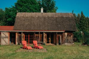 two red chairs sitting in front of a barn at Pommernhaus Forsthaus Rieth am See, Sauna, Kamin, Ruderboot in Rieth