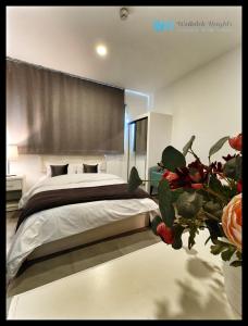Weibdeh Heights Apartments في عمّان: غرفة نوم مع سرير و مزهرية مع الزهور