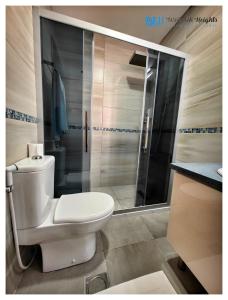 a bathroom with a white toilet and a shower at Weibdeh Heights Apartments in Amman