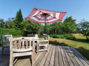 a table with an umbrella and two chairs on a wooden deck at Pommernhaus Charmantes Colonistenhaus, Kamin, Ruderboot in Vorsee