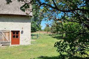 a building with a red door in a field at Pommernhaus Josephinenhof, Sauna, Kamin, Ruderboot in Christianshof