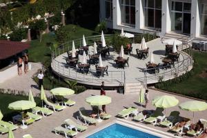 een groep mensen die rond een zwembad met parasols zitten bij white lilyum hotel in Antalya