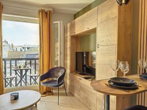 ein Wohnzimmer mit einem Tisch und einem TV in der Unterkunft Le Longchamp in Deauville