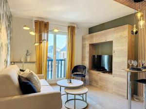 ein Wohnzimmer mit einem Sofa und einem TV in der Unterkunft Le Longchamp in Deauville