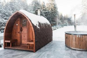 uma casa de hobbit de madeira com uma mesa na neve em Villas Jagoda & Malina em Borovets