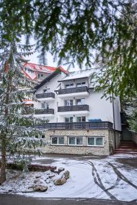 a large white building with snow in front of it at Family TreeZ Premium Apartments in Poiana Brasov