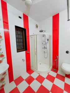 a red and white bathroom with a shower and a toilet at Dream Palace in Alleppey