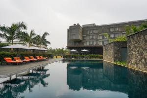 a swimming pool with tables and chairs and a building at Radisson Resort and Spa Lonavala in Lonavala