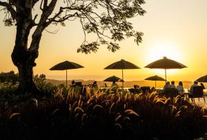 a group of people sitting under umbrellas at sunset at Grün Resort Uluwatu in Uluwatu