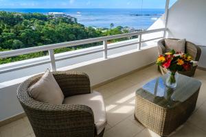 2 chaises et une table avec un vase de fleurs sur le balcon dans l'établissement Grand Large - cosy studio, à Papeete